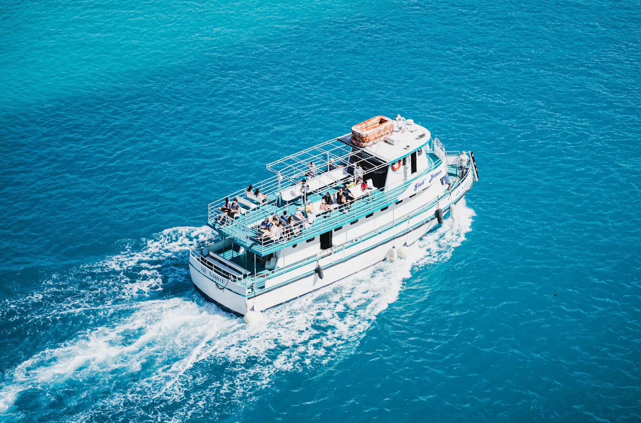 Tour boat full of passengers cruising across turquoise water, seen from above